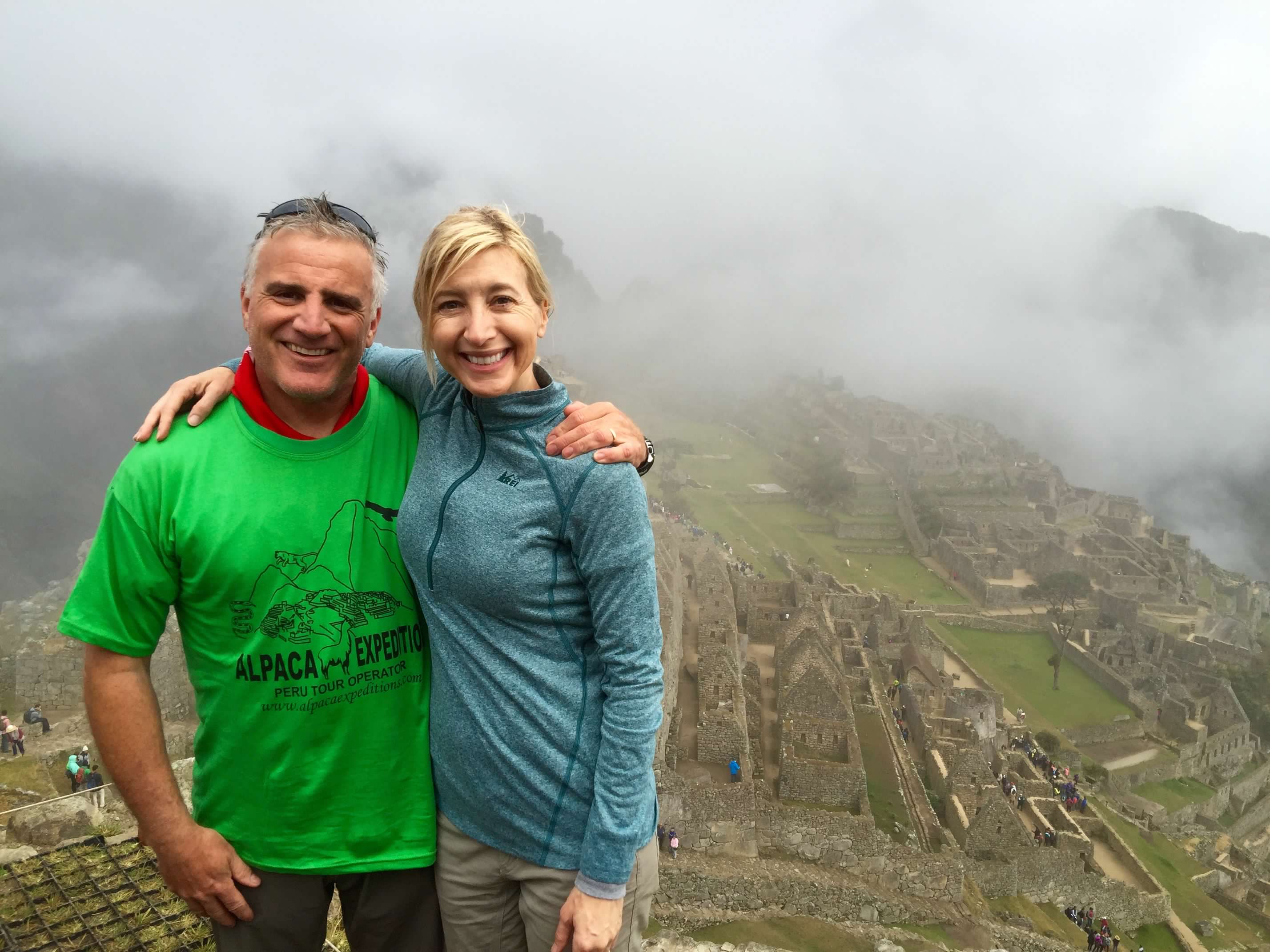 man and woman hikers in front of cloudy Machu Picchu